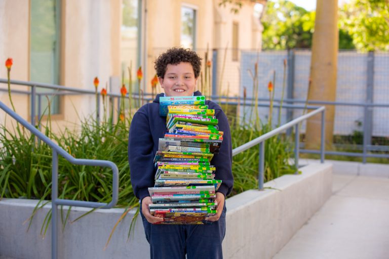 Young boy with a stack of books...smiling.
